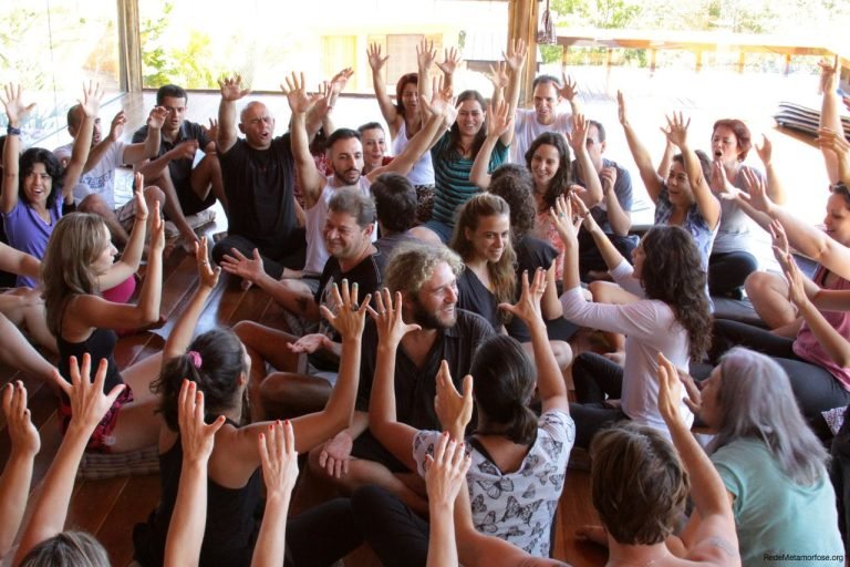 Participantes de uma vivência com as mãos erguidas